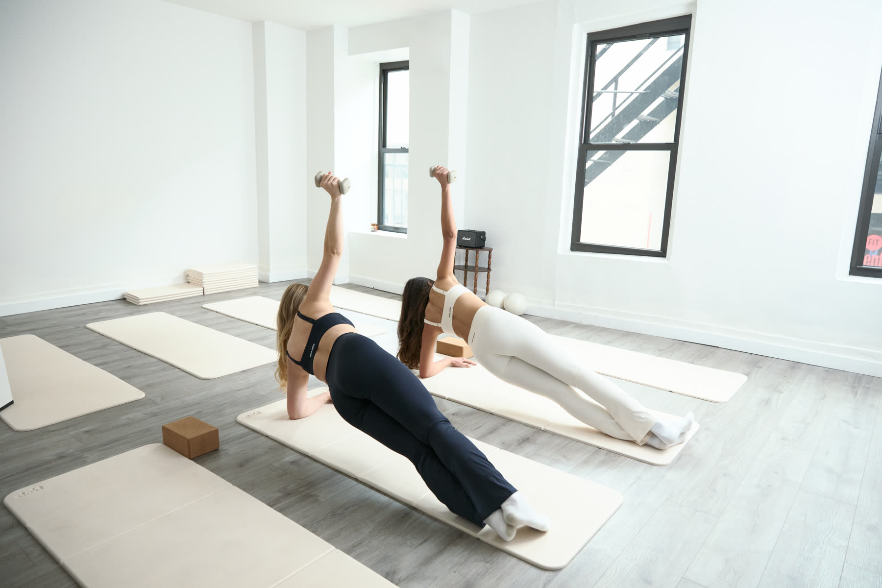 Two women holding side planks in the sunlit stayfor Studio