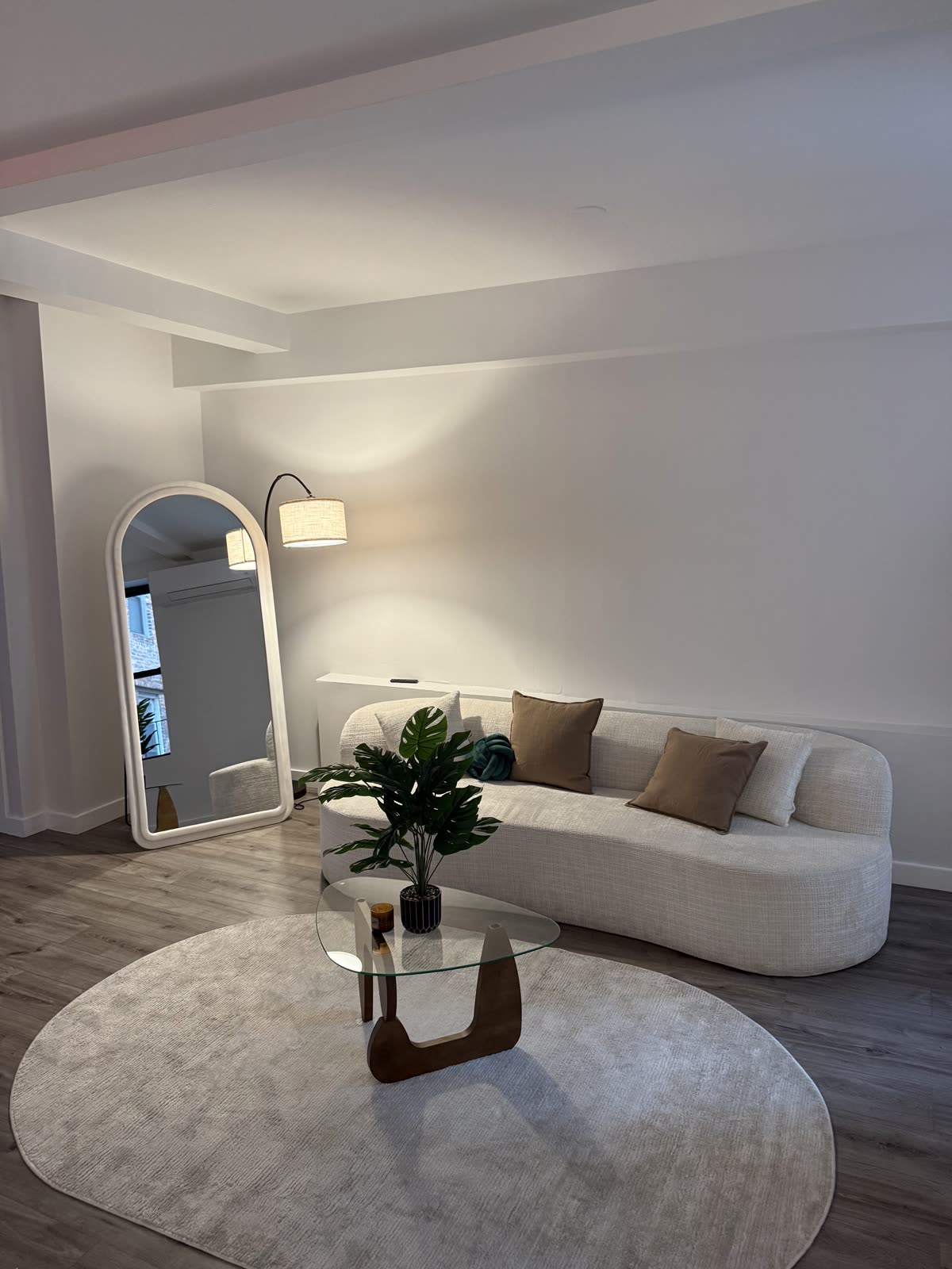 The lounge corner: a curved sofa, rug and arched mirror