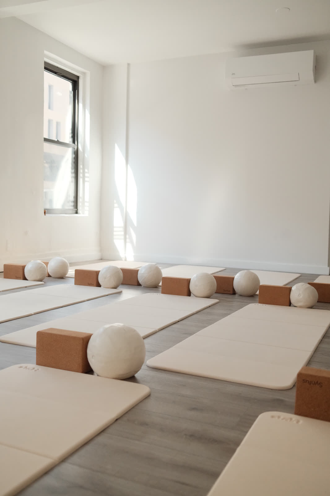 The studio set for class: mats, blocks and pilates balls in afternoon light